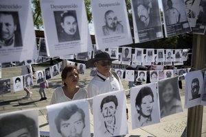 A couple look at images of people who have been disappeared, during a Mother's Day march in Mexico City, Friday, May 10, 2019.