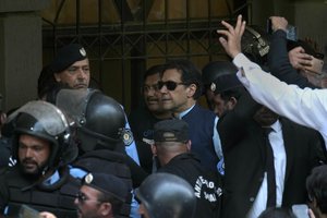 Pakistan's former Prime Minister Imran Khan, center, is escorted by police officers as he arrives to appear in a court, in Islamabad, Pakistan, Friday, May 12, 2023