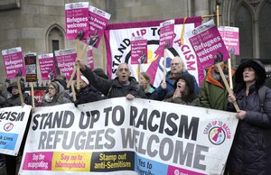 File: Stand Up To Racism campaigners hold banners outside the High Court in London, Monday, Dec. 19, 2022. Judges at Britain’s High Court say the U.K. government’s controversial plan to send asylum-seekers on a one-way trip to Rwanda is legal.