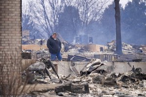 Renato D'Amario looks over what remains after finding his home destroyed by the Marshall Wildfire in Louisville, Colo., Friday, Dec. 31, 2021