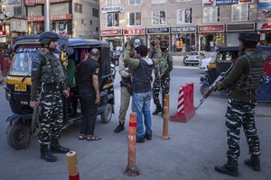 Indian paramilitary soldiers frisk a Kashmiri man at a temporary check point ahead of G20 tourism working group meeting in Srinagar, Indian controlled Kashmir, Saturday, May 20, 2023