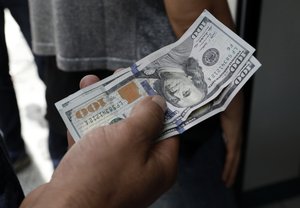 A Turkish waits to change his US dollars with Turkish liras inside a currency exchange shop in Ankara, Turkey, Friday, Aug. 10, 2018.