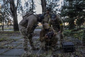 Sniper and commander of a unit in the south, alias Kurt, left, checks real-time drone footage during an operation against Russian positions, Kherson region, southern Ukraine, Saturday, Nov. 19, 2022