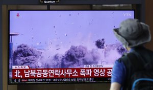 A man watches a TV screen showing a news program with a video of the demolition of the inter-Korean liaison office building in Kaesong, North Korea