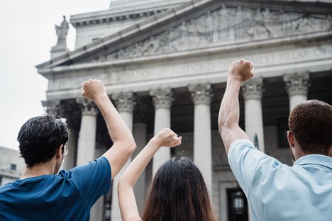 Two men and a woman are protesting in front of the Supreme Court of the United States