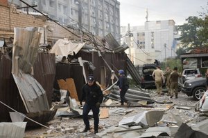 In this photo provided by the National Police of Ukraine, a police officer and a rescue worker walk in front of a restaurant RIA Pizza destroyed by a Russian attack in Kramatorsk, Ukraine, Tuesday, June 27, 2023