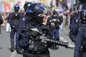 A police officer holds a weapon during a demonstration Thursday, April 13, 2023 in Lille, northern France