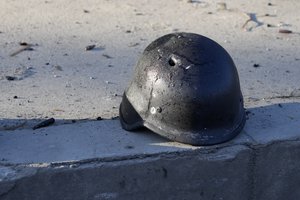 A soldier's helmet with a bullet hole near debris of burning military trucks, in a street in Kyiv, Ukraine, Saturday, Feb. 26, 2022.