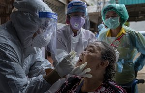 Health workers collect a nasal swab sample from a woman to test for the coronavirus in Bangkok, Thailand, Wednesday, May 6, 2020.