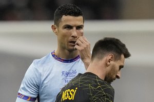 Cristiano Ronaldo gestures is flanked by PSG's Lionel Messi during a friendly soccer match