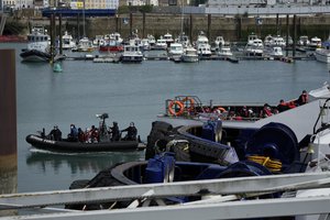 People thought to be migrants who undertook the crossing from France in small boats and were picked up in the Channel are transferred from one British border force vessel, not pictured, which didn't come into the port, as another border vessel at right waits to disembark another group of people thought to be migrants, in Dover, south east England, Friday, June 17, 2022.