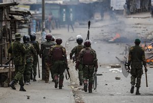 Riot policemen walk past a burning barricade during clashes with protesters in the Mathare area of Nairobi, Kenya Wednesday, July 19, 2023