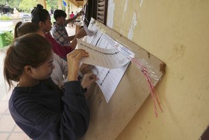 Locals look at a registration list before voting at a polling station on the outskirts of Phnom Penh, Cambodia