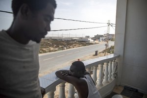 In this Monday, Sept. 23, 2019 photo, Sudanese migrants who tried crossing the Mediterranean from Libya sit in a balcony in a Tunisian Red Crescent facility in Zarzis, south of Tunisia