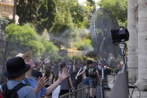 FILE - Tourists cool off near a fan as they queue to enter Rome's Colosseum, July 18, 2023. A new study Tuesday, July 25, finds these intense and deadly hot spells gripping much of the globe in the American Southwest and Southern Europe could not have occurred without climate change.