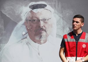 A Turkish police officer walks past a picture of slain Saudi journalist Jamal Khashoggi prior to a ceremony, near the Saudi Arabia consulate in Istanbul, marking the one-year anniversary of his death, Wednesday, Oct. 2, 2019