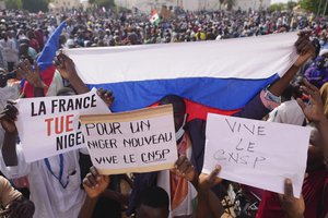 Nigeriens holding a Russian flag and placards participate in a march called by supporters of coup leader Gen. Abdourahmane Tchiani in Niamey, Niger, Sunday, July 30, 2023