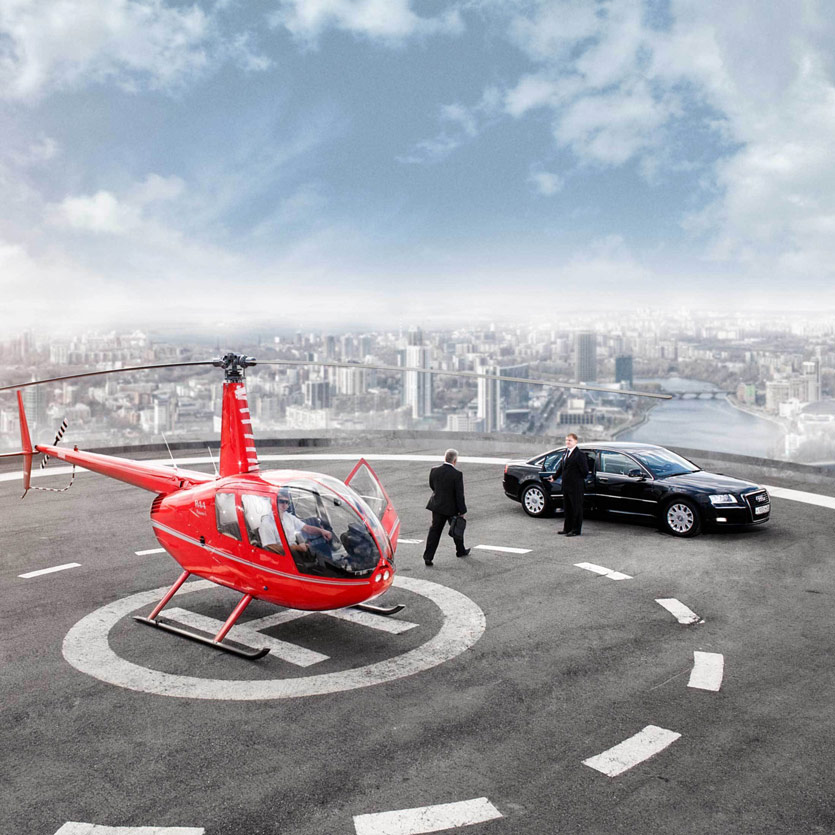 a chauffeur holds open the door to a large Audi as a wealthy businessman exits a helicopter and proceeds across the helipad towards the car