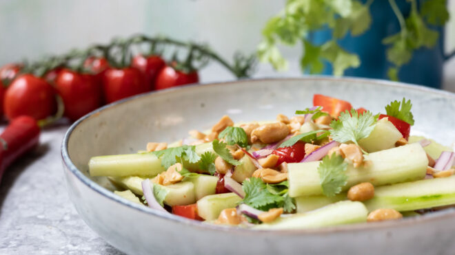 asia agurksalat på tallerken med tomater i bakgrunnen