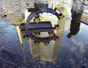 The Euro sculpture in front of the European Central Bank is reflected in a puddle in Frankfurt, Germany, on a rainy and windy Thursday, Jan. 5, 2012