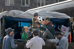 Ethnic Armenian family from Nagorno-Karabakh are helped to leave a truck with their belongings after arriving to Armenia's Goris in Syunik region, Armenia, on Saturday, Sept. 30, 2023.