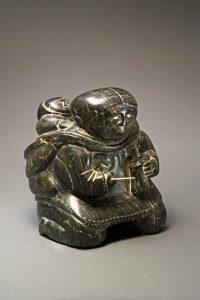 Pinnie (Benjamin) Naktialuk. <em>Mother Sewing Kamik (Skin Boot)</em>, 1954. Stone, ivory, black inlay, 33 x 28.1 x 28.1 cm. Collection of the Winnipeg Art Gallery. Gift of the Women's Committee, G-57-117. Photograph: Ernest Mayer