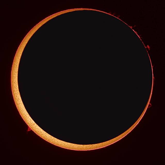 An orange ring of the sun is visible around the moon