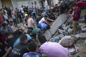 Palestinians look fro survivors after Israeli airstrikes in Khan Younis, Gaza Strip, Monday, Oct. 16, 2023