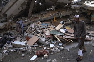 A Palestinian walks by a building destroyed in Israeli bombardment in Rafah refugee camp in Gaza Strip on Tuesday, Oct. 17, 2023.