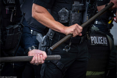 Two cops who are only visible from the chest to waist and are holding batons.