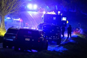 Law enforcement officers, right, stand near armored and tactical vehicles, center, near a property on Meadow Road, in Bowdoin, Maine, Thursday, Oct. 26, 2023