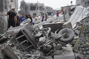 Palestinians walk about buildings destroyed in the Israeli bombardment in the Nusseirat refugee camp in the Gaza Strip on Sunday, Oct. 29, 2023.