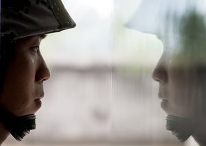 A Chinese soldier is reflected on a window glass as he stands guard during a media visit