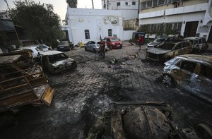 Palestinian men look over the site of a deadly explosion at al-Ahli Hospital in Gaza City