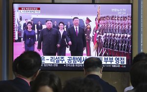 People watch a TV showing North Korean leader Kim Jong Un, second from left, welcoming Chinese President Xi Jinping at Pyongyang airport, at the Seoul Railway Station in Seoul, South Korea, Friday, June 21, 2019