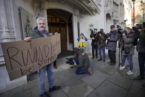 A protester stands outside the Supreme Court in London, Wednesday, Nov. 15, 2023