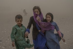 File - Afghan children carry donated aid to their tents, while they are scared and crying from the fierce sandstorm, after an earthquake in Zenda Jan district in Herat province, western of Afghanistan, Thursday, Oct. 12, 2023.