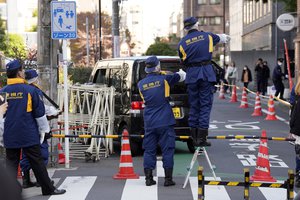 Police officers exam a car, rear, which crashed into a temporary barricade near the Israeli Embassy in Tokyo Thursday, Nov. 16, 2023