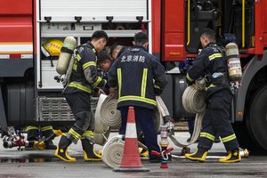 Firefighters load fire hoses near a fire truck after conducting a fire drill at a public park in Beijing, Thursday, April 20, 2023