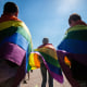 Activists walk with rainbow flags around their shoulders