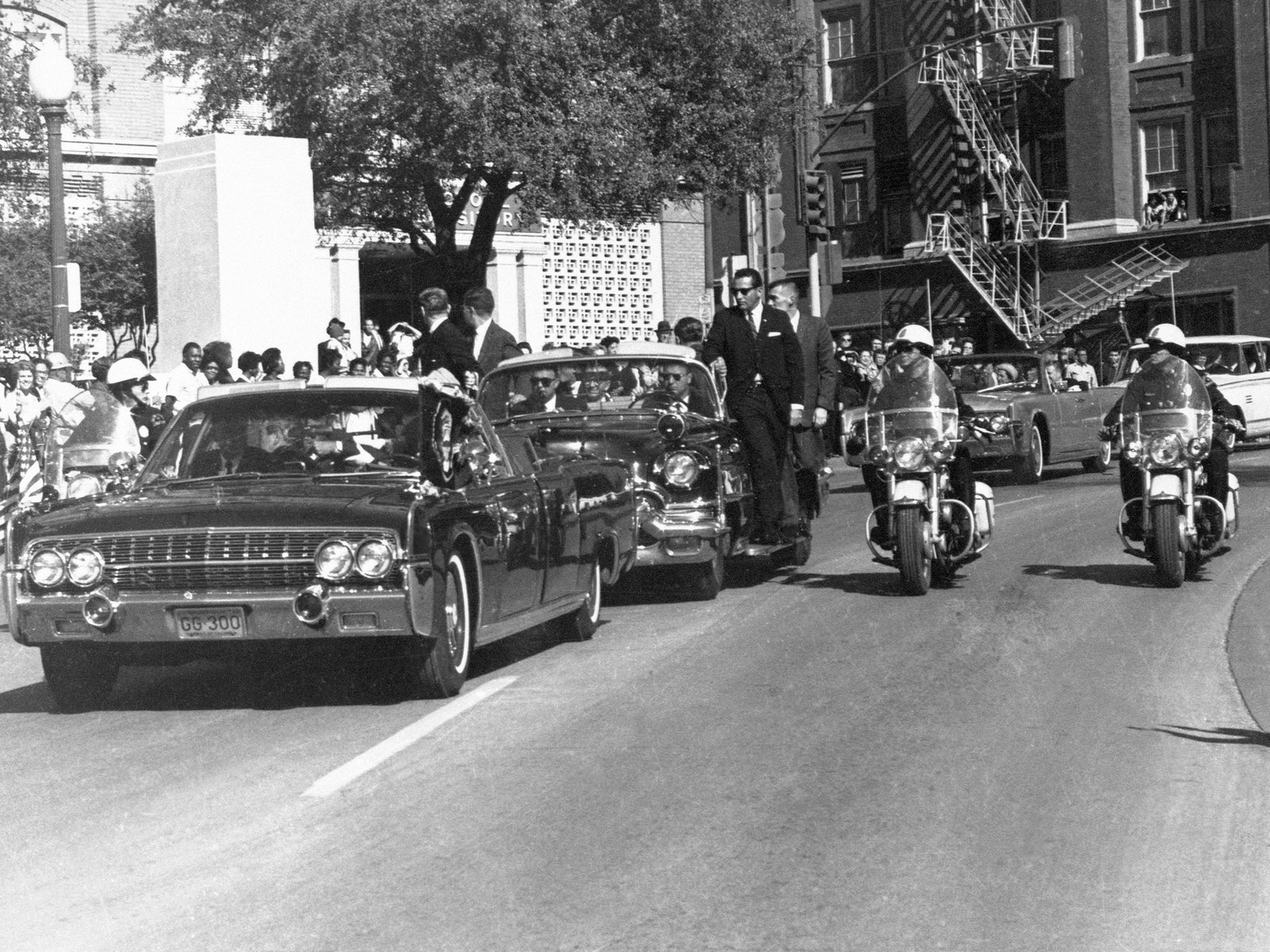 Black and white photograph of President John F. Kennedy's motorcade in Dallas Texas prior to his assassination.