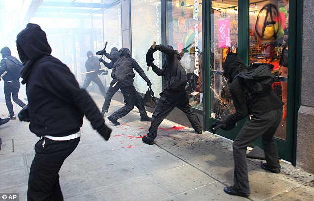 Gang: About two dozen of the hundreds of protesters that participated in the march shattered windows and caused mayhem in Seattle