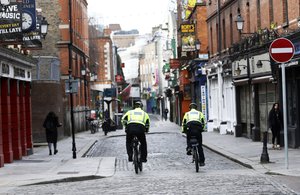 Garda police officers patrol a deserted Temple Bar in Dublin, Ireland, Wednesday, March, 17, 2021