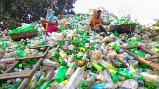 Two women in hijabs sorting through a landfill