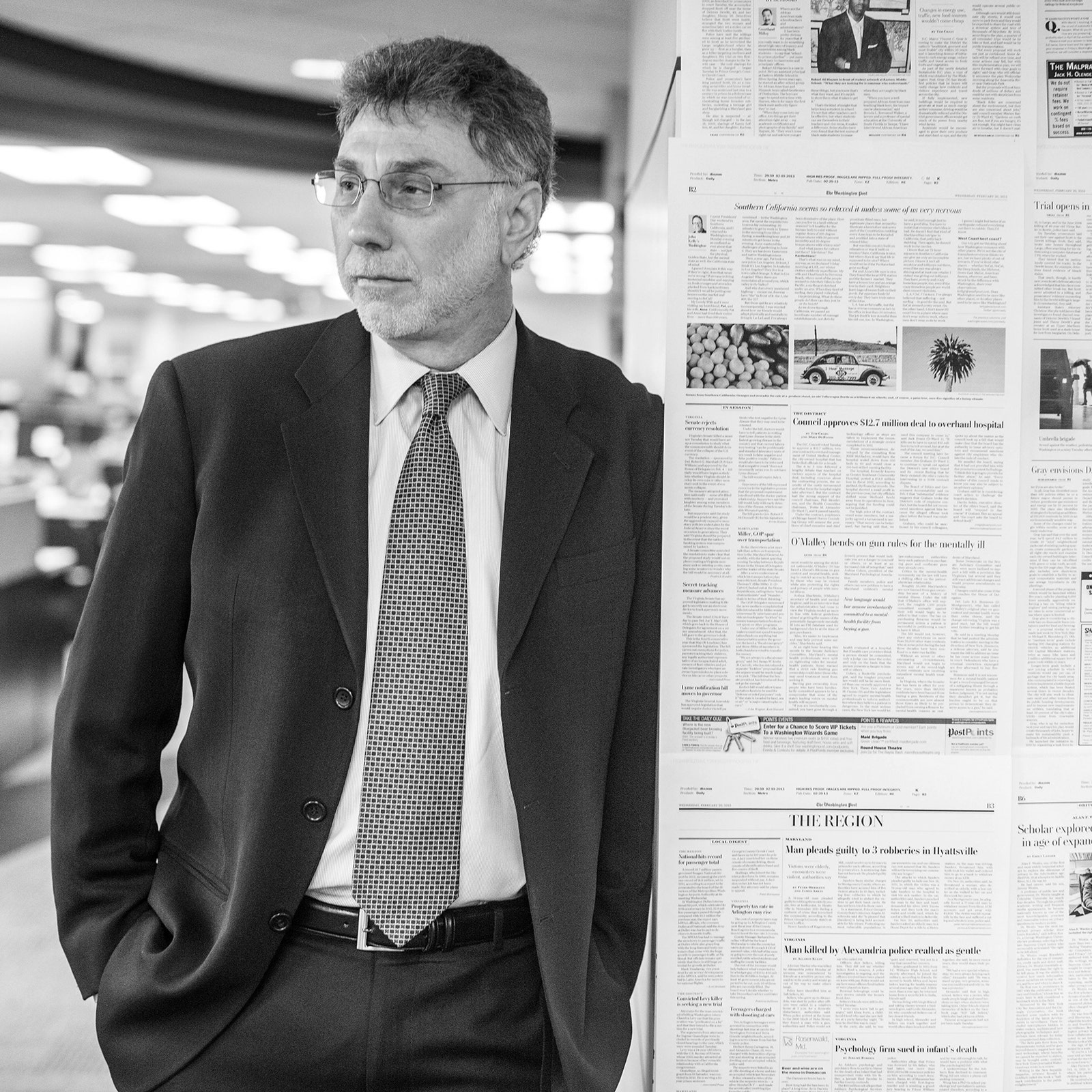 Blackandwhite photograph of Marty Baron standing in a newsroom wearing a suit.