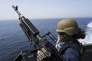 U.S. Navy retail service specialist Artayja Stewart of Clarksville, Tenn., stands guard next to a machine gun aboard the USS Paul Hamilton in the Strait of Hormuz Friday, May 19, 2023.