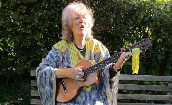 Image of Margret RoadKnight playing guitar and singing.