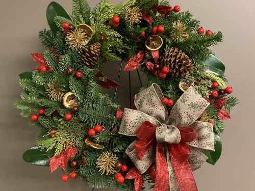 holiday wreath with evergreen leaves and red accents.