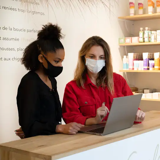 Deux femmes regardant un ordinateur dans un salon de coiffure