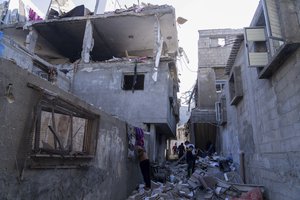 Palestinians inspect a damaged building following Israeli airstrikes on the town of Khan Younis, Gaza, Sunday, Dec. 3, 2023.